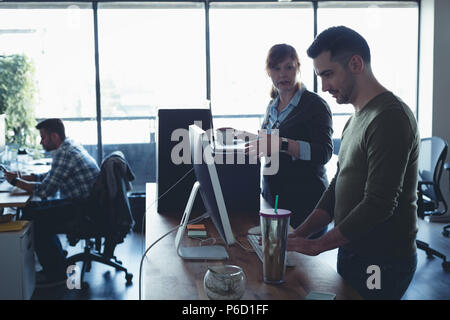 Des collègues en interaction les uns avec les autres tout en travaillant Banque D'Images