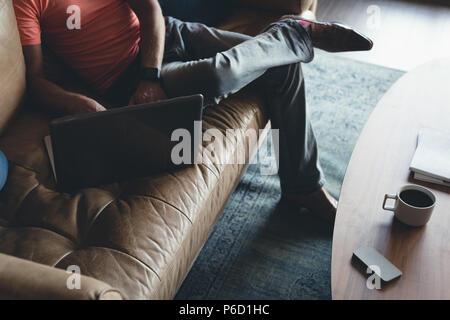 Businessman using laptop on a sofa Banque D'Images