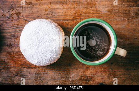 Le petit-déjeuner gratuit. Le café et le sucre en poudre avec krapfen, deux, avec vue de dessus et isolé sur fond de bois. Banque D'Images