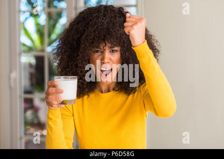 African American Woman holding a glass of milk contrarié et frustré de crier avec colère, fou et hurlant de main levée, la colère concept Banque D'Images