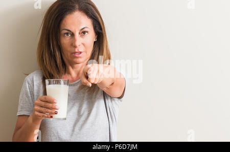 Moyen-âge femme à boire un verre de lait frais pointant avec le doigt à la caméra et à la main, vous signe, positif et confiant geste de la fron Banque D'Images