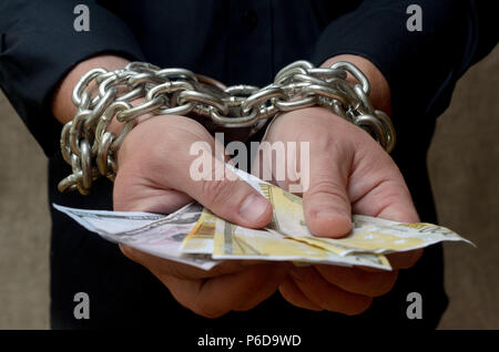 Les mains d'un homme lié par une chaîne et la détention de monnaie. Servitude pour dettes de crédit. Banque D'Images
