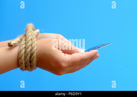 Women's Hands attachés avec une corde et la tenue d'une carte de crédit. Servitude pour dettes de crédit. Banque D'Images