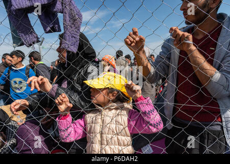 Les réfugiés ressemble à travers la clôture près de la frontière qu'ils attend pour traverser la frontière au camp de réfugiés de fortune de l'Greek-Macedonian bord Banque D'Images