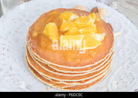 Pile de crêpes fraîchement soutenue sur une plaque vintage avec de la confiture d'orange et les tranches de fruits sur le dessus. Banque D'Images