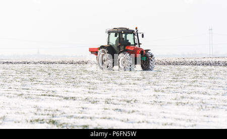 Agriculteur avec tracteur - semis semer les cultures aux champs agricoles en hiver et neige Banque D'Images