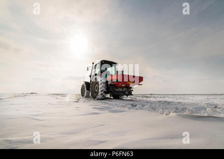 Agriculteur avec tracteur - semis semer les cultures aux champs agricoles en hiver et neige Banque D'Images