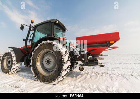 Agriculteur avec tracteur - semis semer les cultures aux champs agricoles en hiver et neige Banque D'Images