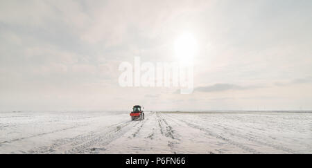 Agriculteur avec tracteur - semis semer les cultures aux champs agricoles en hiver et neige Banque D'Images