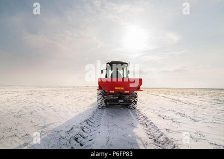 Agriculteur avec tracteur - semis semer les cultures aux champs agricoles en hiver et neige Banque D'Images