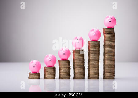 Close-up Pink Piggybank sur l'augmentation des pièces empilées contre fond blanc Banque D'Images