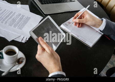 Businessman on business lunch au restaurant sitting at table holding digital tablet écrit dans expresso chaud potable organisateur close-up Banque D'Images