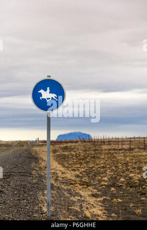 Vertical image de panneau routier à l'est de Reykjavik, Islande. Panneau bleu rond blanc a silhouette d'un cavalier sur un cheval au galop. Banque D'Images