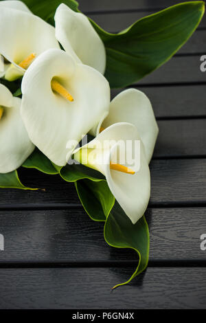 Belle lis calla blancs dans un bouquet sur fond rustique Banque D'Images