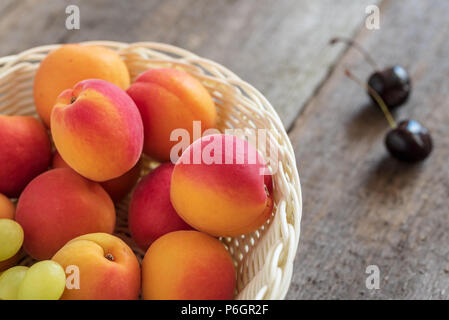 De délicieux abricots mûrs dans un panier sur fond de bois. Banque D'Images