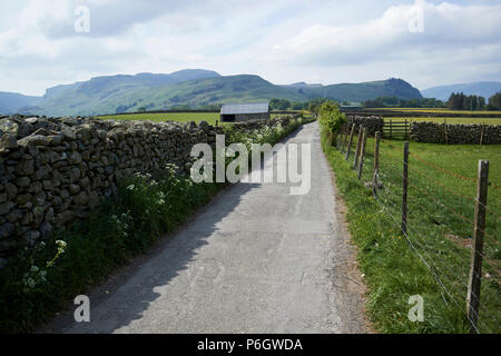 Tarmaced country lane bordée par un mur en pierre sèche et clôture métallique en milieu rural underskiddaw Keswick Cumbria england uk Banque D'Images