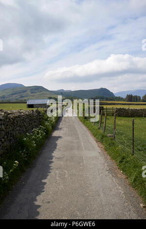 Tarmaced country lane bordée par un mur en pierre sèche et clôture métallique en milieu rural underskiddaw Keswick Cumbria england uk Banque D'Images