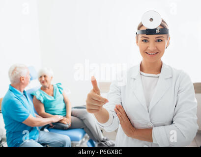 Médecin ORL souriant avec ses patients senior dans l'arrière-plan, l'accent sur le premier plan dans les prix Banque D'Images