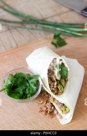 Burrito ou shawurma avec la viande hachée et les haricots verts sur une planche de bois. Focus sélectif. Banque D'Images
