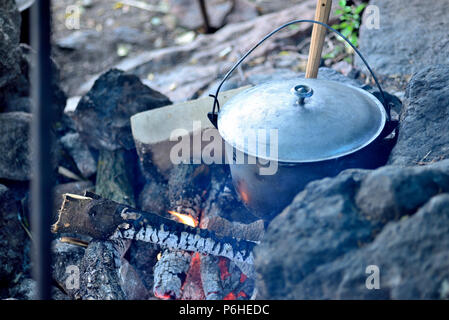 La cuisson dans un chaudron sur un feu ouvert. La préparation des aliments à la participation dans un camping sauvage. pour cuire le dîner dans une casserole en feu. pour manger en plein air dans le camping Banque D'Images
