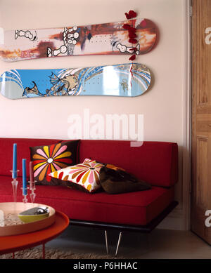 Skateboards à motifs sur le mur au-dessus du canapé rouge iwth coussins lumineux in modern living room Banque D'Images