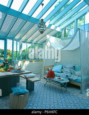 Carrelage marocain et tabouret en bois rustique dans la véranda salon et salle à manger avec canapé-au-dessus de l'auvent voile blanc Banque D'Images