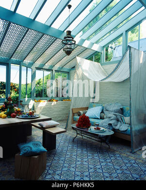 Linge blanc à motifs au-dessus de la canopée un canapé dans la salle de séjour et salle à manger véranda avec tapis bleu à motifs Banque D'Images
