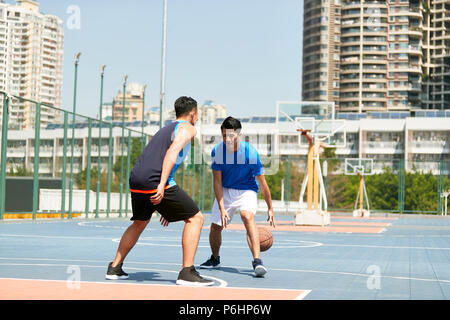 Les jeunes mâles d'Asie de basket-ball jouant seul à seul sur la cour extérieure. Banque D'Images
