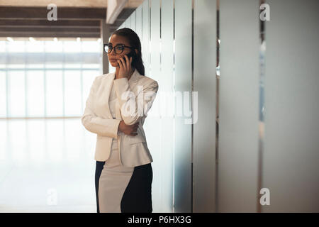 Jeune femme brune à lunettes d'affaires femme parlant par téléphone mobile. Banque D'Images