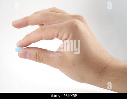 Male hand holding pilule bleue entre les doigts - isolé Banque D'Images