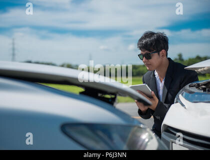 L'inspection d'agent d'assurance voiture endommagée avec formulaire de demande d'assurance sur la tablette numérique Banque D'Images