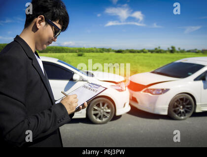 Agent d'assurance, writing on clipboard après accident de voitures. Banque D'Images