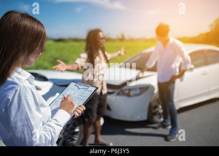 Agent d'assurance, writing on clipboard après accident de voitures. Banque D'Images