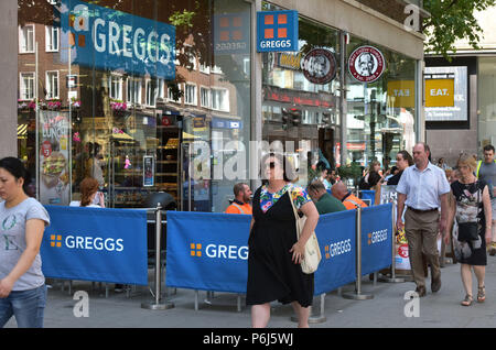 Les gens passent devant une rangée de cafés et des plats à emporter commerces, y compris le fabricant de sandwich et de boulangerie Greggs, Mikel le café et manger. sur Tottenham Court Road dans Banque D'Images