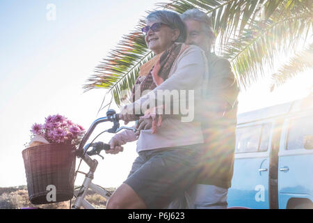 Personnes âgées senior caucasian couple jouer et apprécier l'activité de loisirs piscine de style de vacances. l'homme et la femme prend sa retraite aller sur un vélo vintage comme childre Banque D'Images