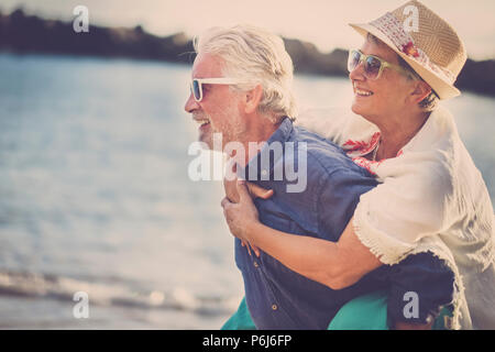 Happy senior couple s'amuser et profiter de l'activité de loisirs de plein air sur la plage. l'homme porter la femme sur le dos pour profiter ensemble un ancien lifestyl Banque D'Images