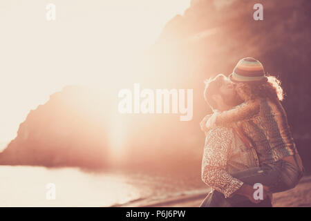 L'âge moyen caucasian couple kissing sur la plage pendant un incroyable coucher du soleil chaud d'or avec ornage et rouge. hugging et entraînant avec passion un Banque D'Images
