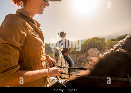 Beau Portrait couple cowboys monter des chevaux dans le vent ladscape lieu pittoresque. femme et homme ensemble s'amuser avec l'ergothérapie et smil apprécier le coucher du soleil. Banque D'Images