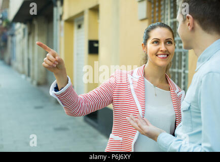 Happy smiling girl aidant les hommes perdus pour trouver moyen de tourisme Banque D'Images