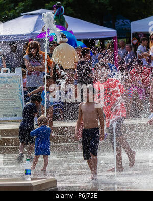 Un garçon hurle en voyant l'eau froide dans les fontaines de Splashville au centre-ville de Asheville, NC, USA Banque D'Images