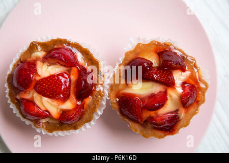 Fromage à la crème aux fraises tartelettes sur la plaque rose, vue du dessus. À partir de ci-dessus, les frais généraux. Libre. Banque D'Images