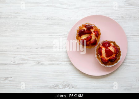 Fromage à la crème aux fraises tartelettes sur la plaque rose, à partir de ci-dessus. Copier l'espace. Banque D'Images