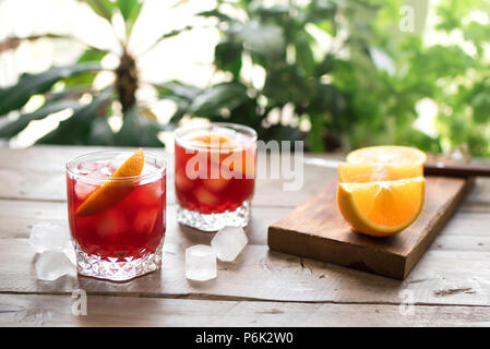 Negroni Cocktail avec de l'orange et la glace. Cocktail Negroni classique fait maison et les ingrédients sur la table en bois, copie de l'espace. Banque D'Images