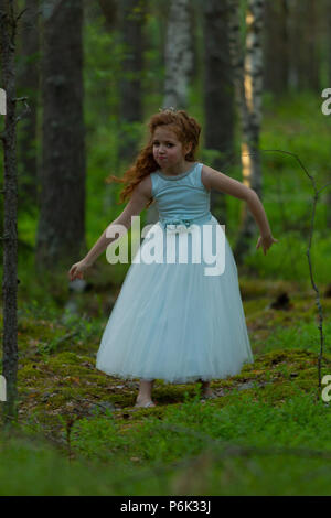 Petite fille émotionnelle dans une robe de princesse dans une forêt d'été, la lumière naturelle Banque D'Images