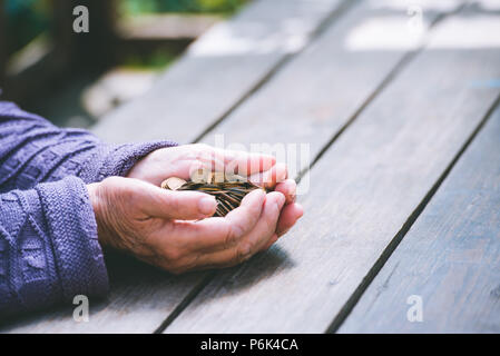 L'argent, de monnaie, de la grand-mère sur les pensions et la notion de vie, minimum - mains de la vieille femme à occuper une poignée de pièces sur une table en bois Banque D'Images