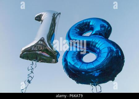 Deux ballons d'hélium pour célébrer un 18e anniversaire partie contre un ciel bleu au crépuscule Banque D'Images