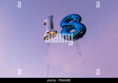 Deux ballons d'hélium pour célébrer un 18e anniversaire partie contre un ciel bleu au crépuscule Banque D'Images