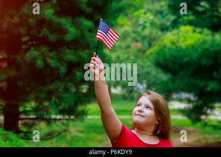 Adorable petite fille holding american flag sur belle journée d'été. 4e jour de l'indépendance de juillet, fête en plein air. Banque D'Images