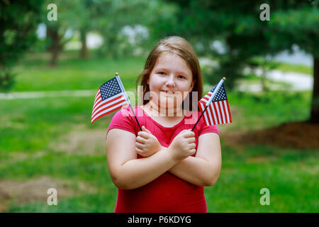 Rire petite fille avec de longs cheveux blonds holding drapeau américain et l'agitant d', extérieur portrait sur journée ensoleillée dans Independence Day et le Jour du drapeau Banque D'Images