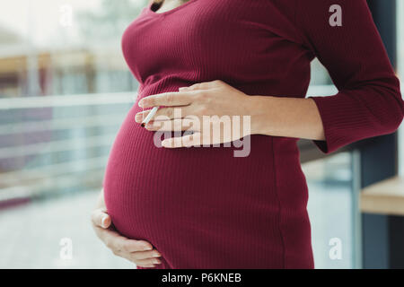 Le tabagisme de la femme enceinte et de toucher son gros ventre Banque D'Images